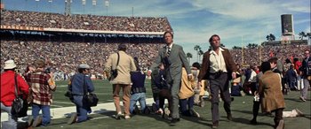 Movie still from “Black Sunday” (1977), directed by John Frankenheimer – A group of men walking across a football field; Wide shot, Low angle