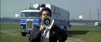 Movie still from “Black Sunday” (1977), directed by John Frankenheimer – A man holding a speaker in front of his face; Medium shot, Low angle