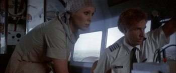 Movie still from “Black Sunday” (1977), directed by John Frankenheimer – A woman wearing a head scarf looking out the window of an airplane; Medium shot, Low angle