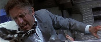 Movie still from “Black Sunday” (1977), directed by John Frankenheimer – A man in a suit and tie sitting in a car; Close Up shot, Overhead angle