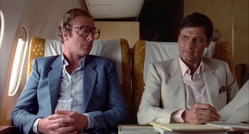 Movie still from “Blame It on Rio” (1984), directed by Stanley Donen – Two men sitting next to each other on a plane; Medium shot, Low angle