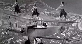 Movie still from “Blame It on Rio” (1984), directed by Stanley Donen – A group of people standing on top of an airplane in the air; Wide shot, Low angle