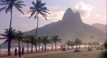 Movie still from “Blame It on Rio” (1984), directed by Stanley Donen – A car driving down a street next to palm trees; Extreme Wide shot, Low angle