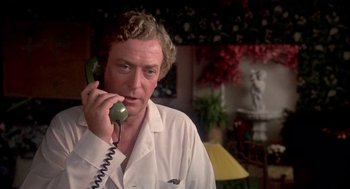 Movie still from “Blame It on Rio” (1984), directed by Stanley Donen – A man talking on a phone while wearing a lab coat; Close Up shot, Low angle
