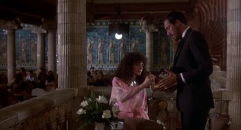 Movie still from “Blame It on Rio” (1984), directed by Stanley Donen – A man and a woman are holding hands in front of an egyptian scene; Medium shot, Low angle