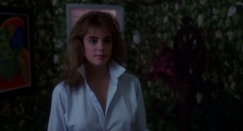 Movie still from “Blame It on Rio” (1984), directed by Stanley Donen – A woman in a white dress shirt is standing in front of a bush; Close Up shot, Over the shoulder angle