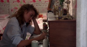 Movie still from “Blame It on Rio” (1984), directed by Stanley Donen – A woman sitting on a bed looking at a dresser; Medium shot, High angle