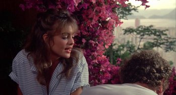 Movie still from “Blame It on Rio” (1984), directed by Stanley Donen – A woman sitting in front of a pink flower bush; Medium shot, Over the shoulder angle