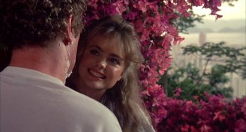 Movie still from “Blame It on Rio” (1984), directed by Stanley Donen – A man and a woman are looking at each other in front of some flowers; Close Up shot, Over the shoulder angle