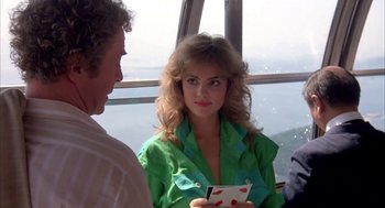 Movie still from “Blame It on Rio” (1984), directed by Stanley Donen – A woman in a green shirt is holding a card; Medium shot, Over the shoulder angle