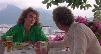 Movie still from “Blame It on Rio” (1984), directed by Stanley Donen – A woman and a man sitting at a dinner table; Medium shot, Over the shoulder angle