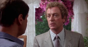 Movie still from “Blame It on Rio” (1984), directed by Stanley Donen – A man wearing a suit and tie talking to another man wearing a suit and tie; Close Up shot, Over the shoulder angle