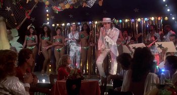 Movie still from “Blame It on Rio” (1984), directed by Stanley Donen – A group of people standing in a room with lights; Wide shot, Low angle