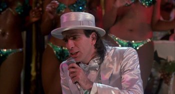 Movie still from “Blame It on Rio” (1984), directed by Stanley Donen – A man wearing a white hat is holding a microphone; Close Up shot, Low angle