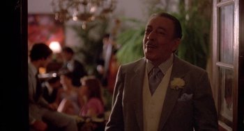Movie still from “Blame It on Rio” (1984), directed by Stanley Donen – A man in a suit and tie standing in front of a crowd; Close Up shot, Over the shoulder angle