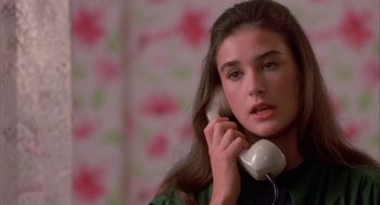 Movie still from “Blame It on Rio” (1984), directed by Stanley Donen – A woman holding a phone to her ear while standing in front of a wall; Close Up shot, High angle