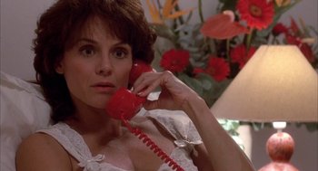 Movie still from “Blame It on Rio” (1984), directed by Stanley Donen – A woman holding a red phone up to her ear; Close Up shot, High angle