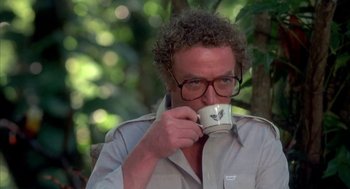 Movie still from “Blame It on Rio” (1984), directed by Stanley Donen – A man drinking a cup of coffee while sitting on a bench; Close Up shot, Low angle