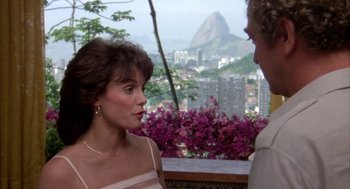 Movie still from “Blame It on Rio” (1984), directed by Stanley Donen – A woman and a man standing next to each other in front of mountains; Close Up shot, Over the shoulder angle