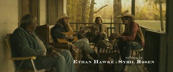 Movie still from “Blaze” (2018), directed by Ethan Hawke – A group of people sitting on a porch with a guitar; Wide shot, Over the shoulder angle