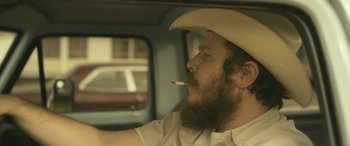 Movie still from “Blaze” (2018), directed by Ethan Hawke – A man in a cowboy hat is smoking a cigarette; Close Up shot, Low angle