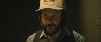 Movie still from “Blaze” (2018), directed by Ethan Hawke – A man with a beard wearing a hat; Close Up shot, Over the shoulder angle