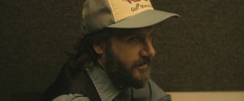 Movie still from “Blaze” (2018), directed by Ethan Hawke – A man with a beard wearing a hat; Close Up shot, Over the shoulder angle