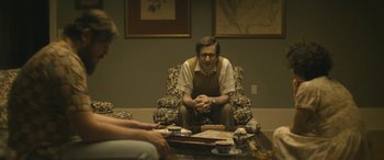 Movie still from “Blaze” (2018), directed by Ethan Hawke – A man sitting on a chair in front of a table; Medium shot, Over the shoulder angle