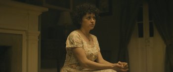 Movie still from “Blaze” (2018), directed by Ethan Hawke – A woman sitting on a chair in front of a lamp; Medium shot, Over the shoulder angle