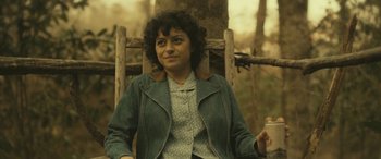 Movie still from “Blaze” (2018), directed by Ethan Hawke – A woman sitting in a chair holding a drink; Medium shot, Over the shoulder angle