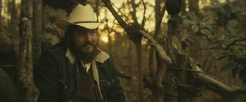 Movie still from “Blaze” (2018), directed by Ethan Hawke – A man with a beard wearing a cowboy hat; Medium shot, Over the shoulder angle