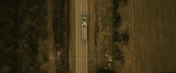 Movie still from “Blaze” (2018), directed by Ethan Hawke – An aerial view of a truck driving down a road; Extreme Wide shot, Overhead angle