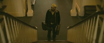 Movie still from “Blaze” (2018), directed by Ethan Hawke – A man in a cowboy hat carrying a guitar case down a flight of stairs; Medium shot, Low angle