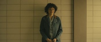 Movie still from “Blaze” (2018), directed by Ethan Hawke – A woman standing in front of a brick wall; Medium shot, High angle