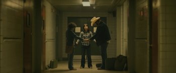 Movie still from “Blaze” (2018), directed by Ethan Hawke – A group of people standing around each other in a hallway; Wide shot, High angle