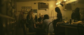Movie still from “Blaze” (2018), directed by Ethan Hawke – A group of people sitting around a table playing cards; Medium shot, High angle