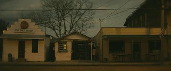 Movie still from “Blaze” (2018), directed by Ethan Hawke – A man standing in front of a building on the side of the road; Extreme Wide shot, Low angle