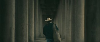 Movie still from “Blaze” (2018), directed by Ethan Hawke – A man in a cowboy hat is walking through an alley way; Wide shot, Low angle