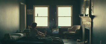 Movie still from “Blaze” (2018), directed by Ethan Hawke – A person sitting on a bed watching television; Wide shot, High angle