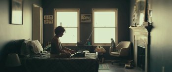 Movie still from “Blaze” (2018), directed by Ethan Hawke – A woman sitting on a bed in a room with a cat; Wide shot, Low angle