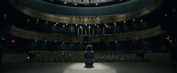 Movie still from “Blaze” (2018), directed by Ethan Hawke – A woman sitting on the floor of a theater; Extreme Wide shot, High angle