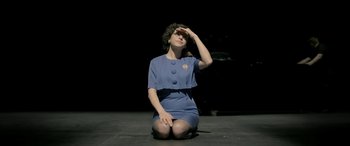 Movie still from “Blaze” (2018), directed by Ethan Hawke – A woman sitting on the ground with her hand on her forehead; Medium shot, Overhead angle