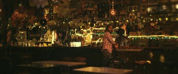 Movie still from “Blaze” (2018), directed by Ethan Hawke – A man standing at a table in front of a bar; Wide shot, Low angle
