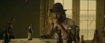 Movie still from “Blaze” (2018), directed by Ethan Hawke – A man sitting at a table eating a piece of food; Medium shot, Low angle