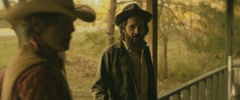 Movie still from “Blaze” (2018), directed by Ethan Hawke – A man with a beard wearing a hat and a jacket; Medium shot, Over the shoulder angle