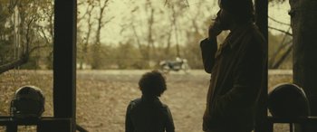 Movie still from “Blaze” (2018), directed by Ethan Hawke – A man and a child standing in the dirt; Medium shot, Over the shoulder angle