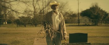 Movie still from “Blaze” (2018), directed by Ethan Hawke – An older man holding a bunch of sticks in his hand; Medium shot, Low angle