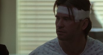 Movie still from “Blind Horizon” (2003), directed by Michael Haussman – A man with bandages on his head and a bandage on his forehead; Close Up shot, Over the shoulder angle
