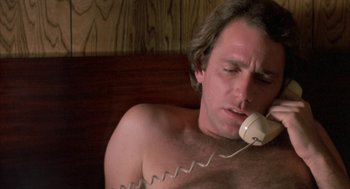 Movie still from “Blood Simple” (1984), directed by Joel Coen – A shirtless man talking on a phone while lying in bed; Close Up shot, Low angle