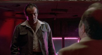Movie still from “Blood Simple” (1984), directed by Joel Coen – A man standing in front of a window in a room; Medium shot, Low angle